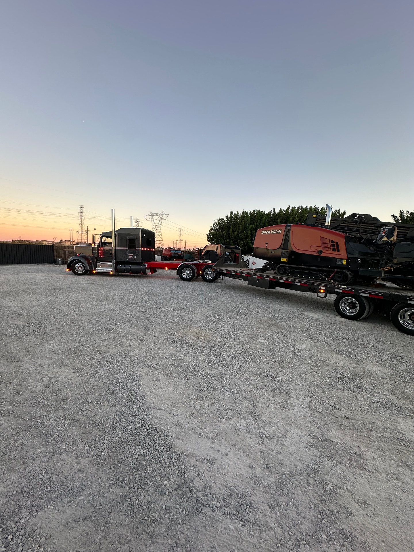 Peterbilt and lowboy loaded with the JT rig at sunset